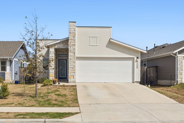 view of front of home featuring a garage, concrete driveway, stone siding, fence, and stucco siding