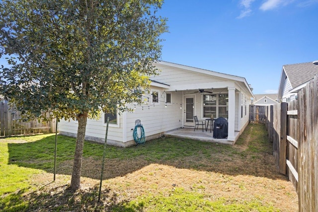 rear view of property with a ceiling fan, a fenced backyard, a patio, and a lawn