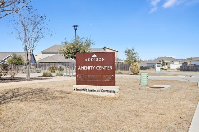 community / neighborhood sign featuring a lawn, fence, and a residential view