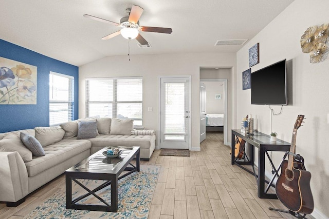 living room featuring vaulted ceiling, light wood finished floors, visible vents, and a ceiling fan