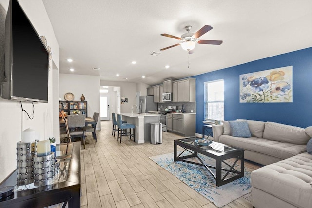 living room with light wood-type flooring, visible vents, a ceiling fan, and recessed lighting