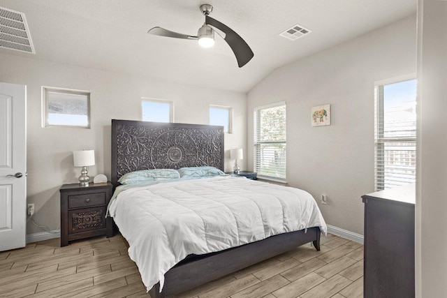 bedroom with lofted ceiling, wood tiled floor, visible vents, and baseboards