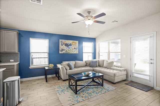 living area with wood finish floors, visible vents, ceiling fan, and lofted ceiling