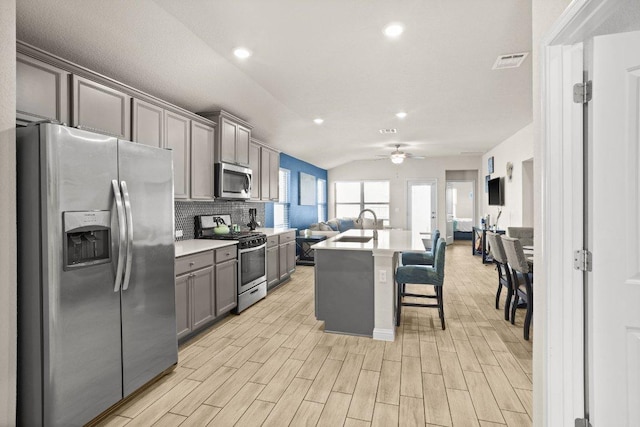 kitchen featuring gray cabinets, visible vents, backsplash, appliances with stainless steel finishes, and open floor plan