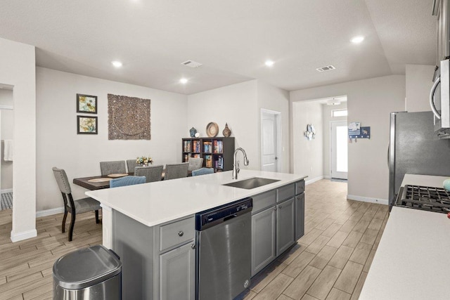 kitchen featuring visible vents, gray cabinetry, stainless steel dishwasher, wood tiled floor, and a sink