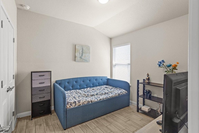 bedroom with baseboards, vaulted ceiling, and wood finish floors