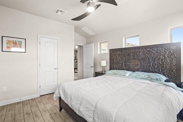 bedroom with wood finished floors, a ceiling fan, visible vents, vaulted ceiling, and baseboards