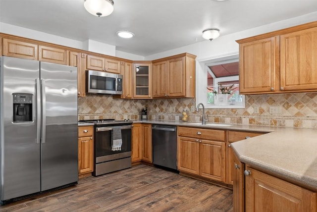 kitchen featuring stainless steel appliances, dark wood-style flooring, a sink, and decorative backsplash