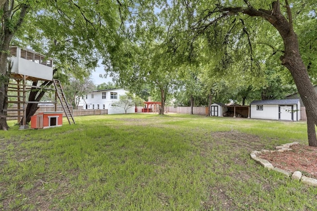 view of yard with an outbuilding, fence, a sunroom, stairs, and a storage unit