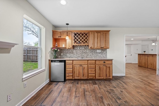 kitchen with dishwashing machine, dark wood-type flooring, baseboards, hanging light fixtures, and decorative backsplash