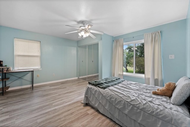 bedroom featuring ceiling fan, baseboards, a closet, and wood finished floors