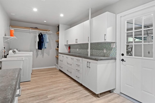 clothes washing area featuring recessed lighting, baseboards, cabinet space, light wood finished floors, and washing machine and clothes dryer