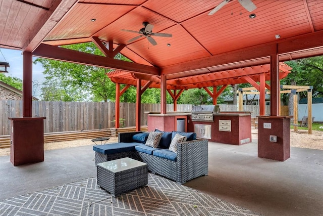 view of patio with outdoor lounge area, a fenced backyard, an outdoor kitchen, and a gazebo