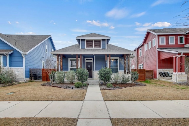 bungalow-style house featuring covered porch, a front lawn, a shingled roof, and fence