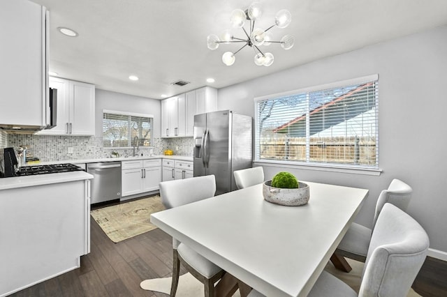 kitchen with dark wood-type flooring, visible vents, white cabinetry, appliances with stainless steel finishes, and tasteful backsplash