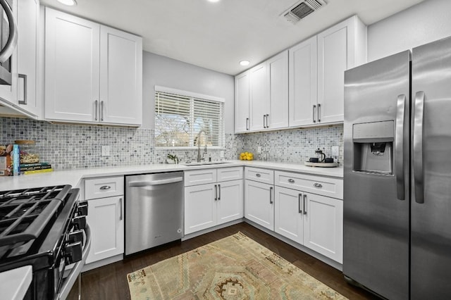 kitchen featuring stainless steel appliances, a sink, visible vents, light countertops, and dark wood-style floors