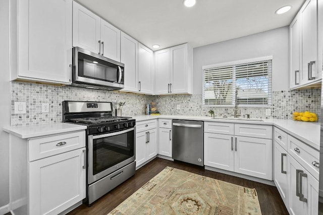 kitchen featuring stainless steel appliances, a sink, white cabinets, light countertops, and dark wood finished floors