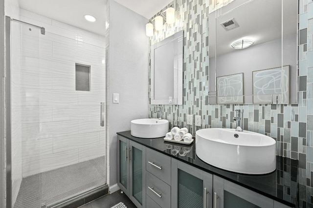 full bath with a stall shower, visible vents, a sink, and double vanity