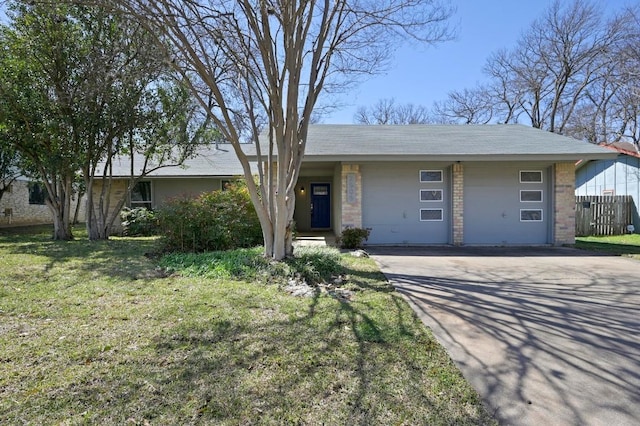 view of front of home with brick siding, an attached garage, fence, driveway, and a front lawn