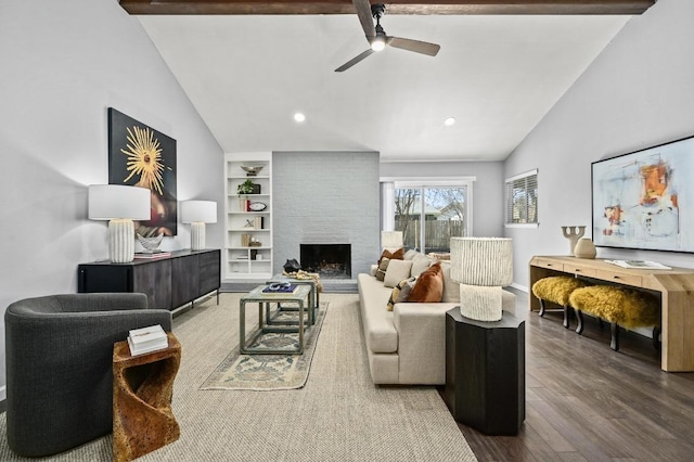 living room with ceiling fan, a fireplace, wood finished floors, built in features, and beamed ceiling