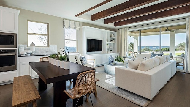 living room featuring a healthy amount of sunlight, built in features, dark wood-style flooring, and beamed ceiling