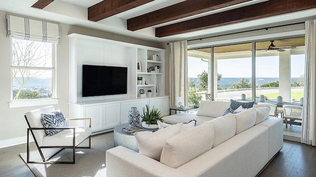 living room featuring built in shelves, beam ceiling, dark wood-style flooring, a ceiling fan, and baseboards