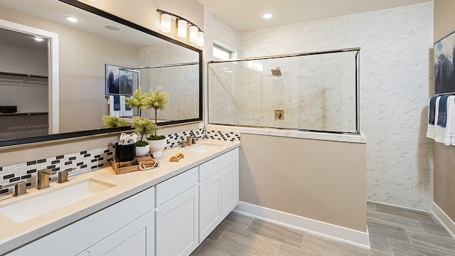 full bath featuring a walk in shower, double vanity, tasteful backsplash, and a sink