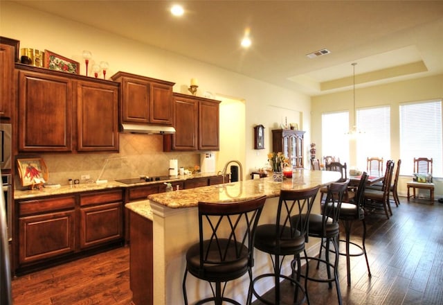 kitchen featuring tasteful backsplash, visible vents, dark wood-style flooring, and a tray ceiling