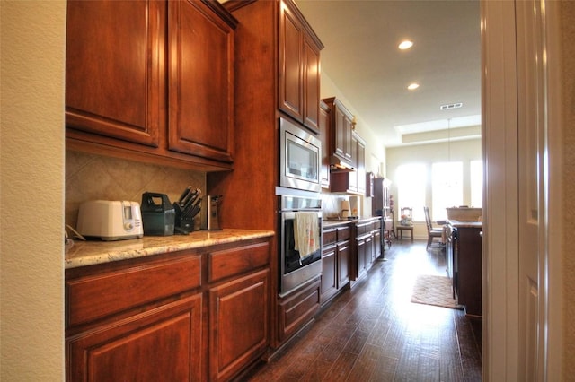 kitchen with visible vents, dark wood finished floors, decorative backsplash, appliances with stainless steel finishes, and light stone countertops