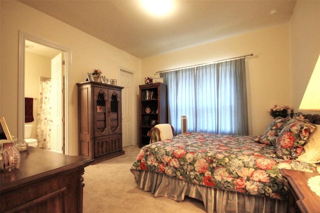 bedroom featuring light carpet and ensuite bathroom