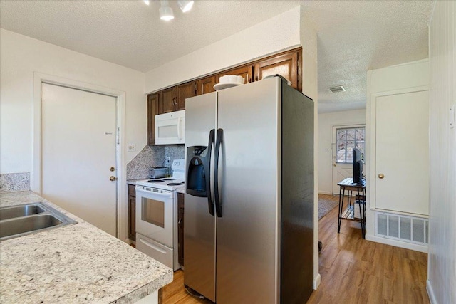 kitchen with white appliances, a sink, visible vents, light wood-style floors, and light countertops