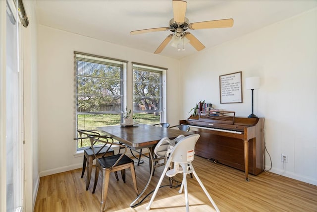 dining space featuring light wood-type flooring, baseboards, and a ceiling fan