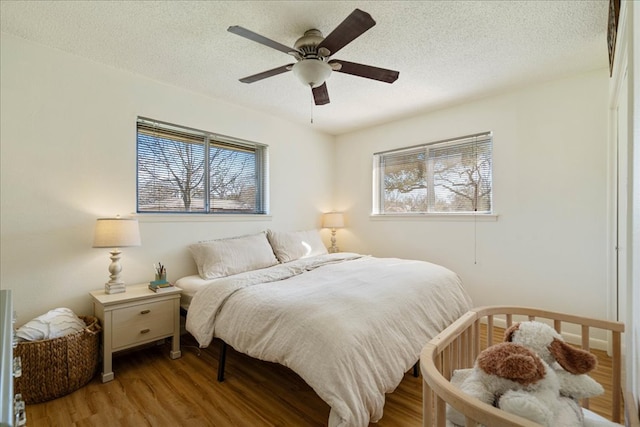 bedroom with a textured ceiling, ceiling fan, and wood finished floors