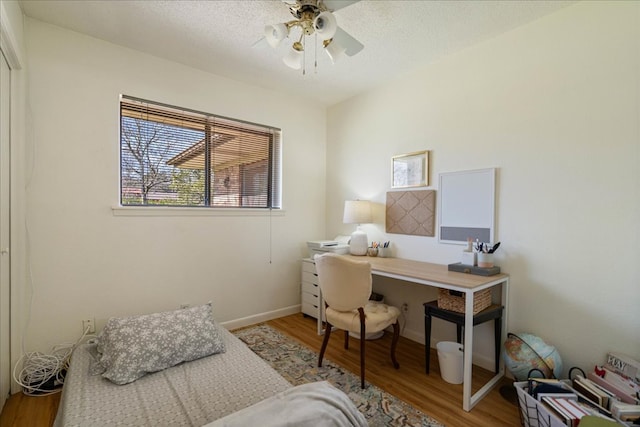 bedroom with baseboards, a textured ceiling, a ceiling fan, and wood finished floors