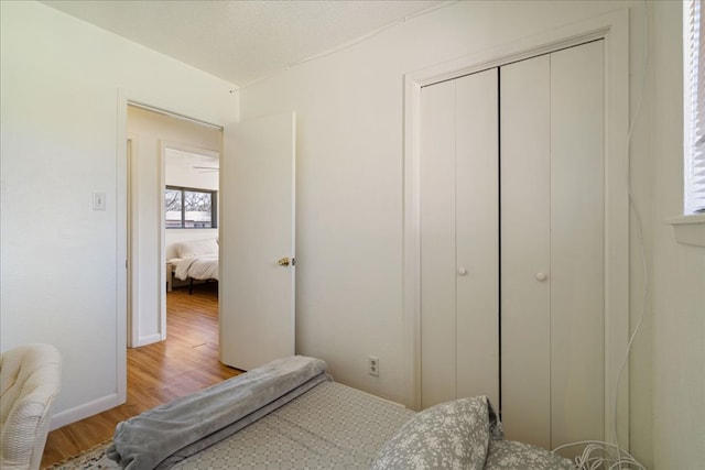 bedroom with a closet, baseboards, a textured ceiling, and light wood finished floors