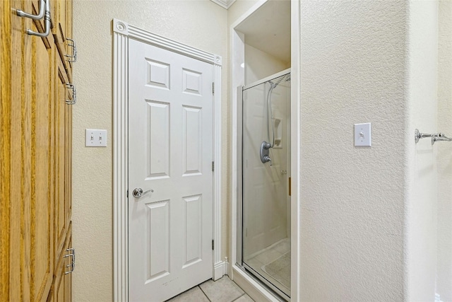 full bathroom featuring a textured wall, a shower stall, and tile patterned floors