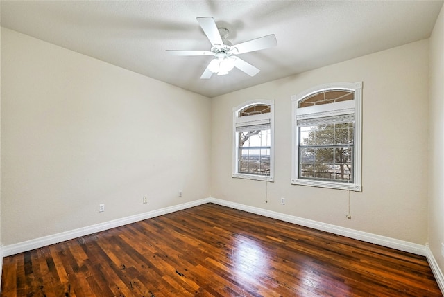 unfurnished room featuring a ceiling fan, baseboards, and dark wood-type flooring