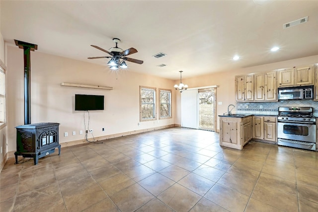 kitchen featuring visible vents, open floor plan, appliances with stainless steel finishes, tasteful backsplash, and a wood stove