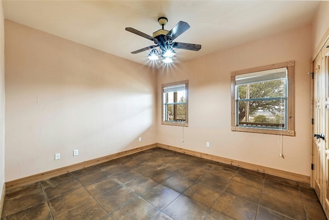 spare room featuring ceiling fan and baseboards