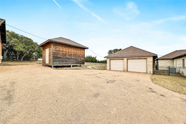 view of home's exterior with an outbuilding, a shingled roof, fence, and a garage