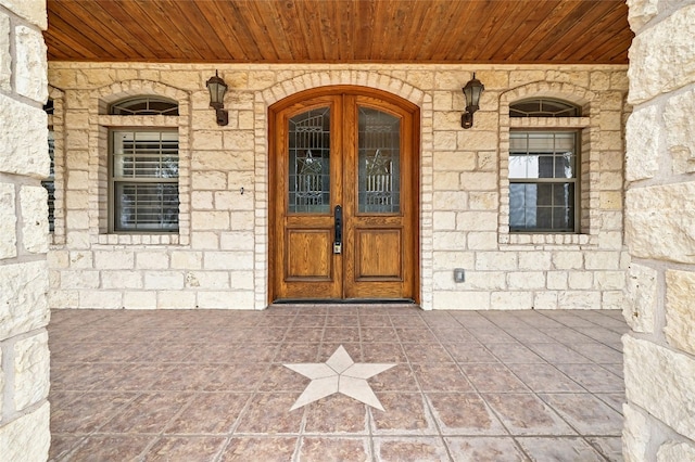 view of exterior entry with stone siding and covered porch