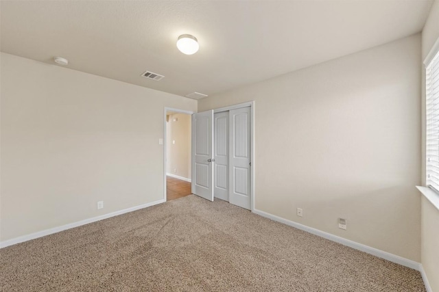 unfurnished bedroom featuring a closet, carpet, visible vents, and baseboards