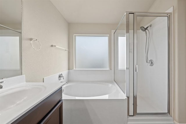 bathroom featuring a textured wall, a stall shower, a garden tub, and vanity