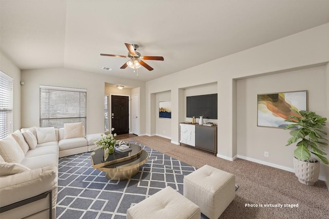 carpeted living area with a ceiling fan, visible vents, vaulted ceiling, and baseboards