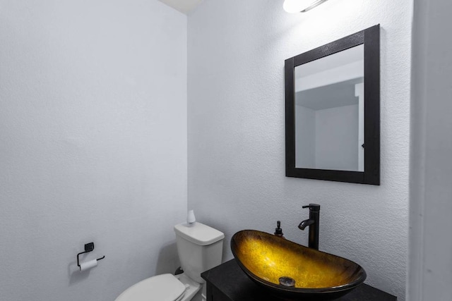 half bath with a textured wall, a sink, and toilet