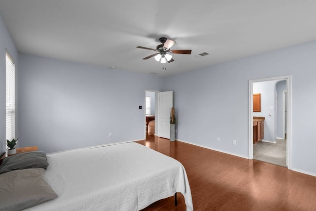 bedroom featuring baseboards, visible vents, dark wood finished floors, ceiling fan, and ensuite bathroom