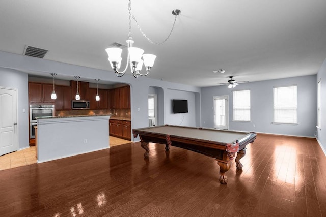 recreation room featuring baseboards, visible vents, arched walkways, light wood-type flooring, and ceiling fan with notable chandelier