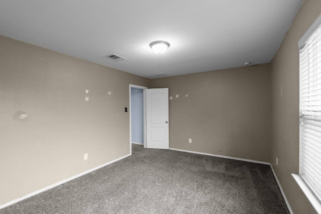 unfurnished room with carpet, visible vents, and baseboards