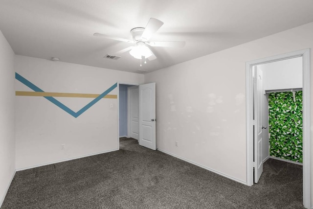 empty room with a ceiling fan, visible vents, dark carpet, and baseboards