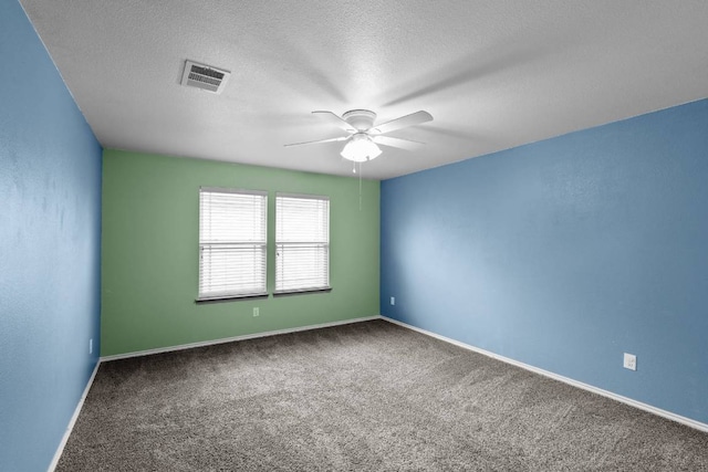 spare room featuring a textured ceiling, carpet flooring, visible vents, and baseboards